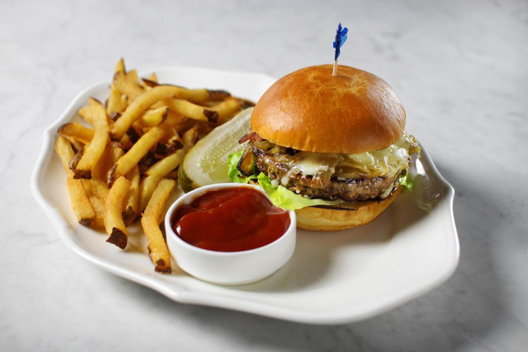 A burger with fries and ketchup on a white plate