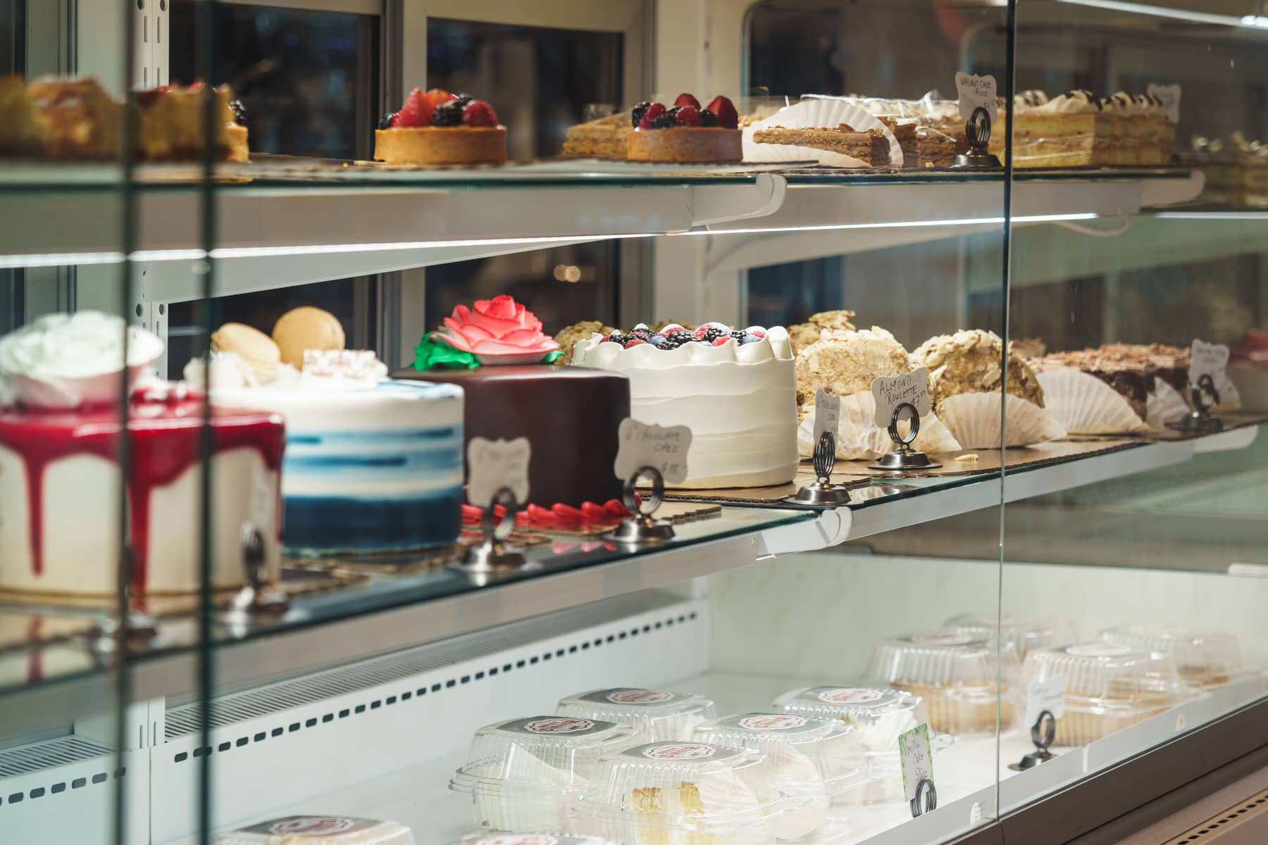 A glass display case filled with various cakes and pastries.