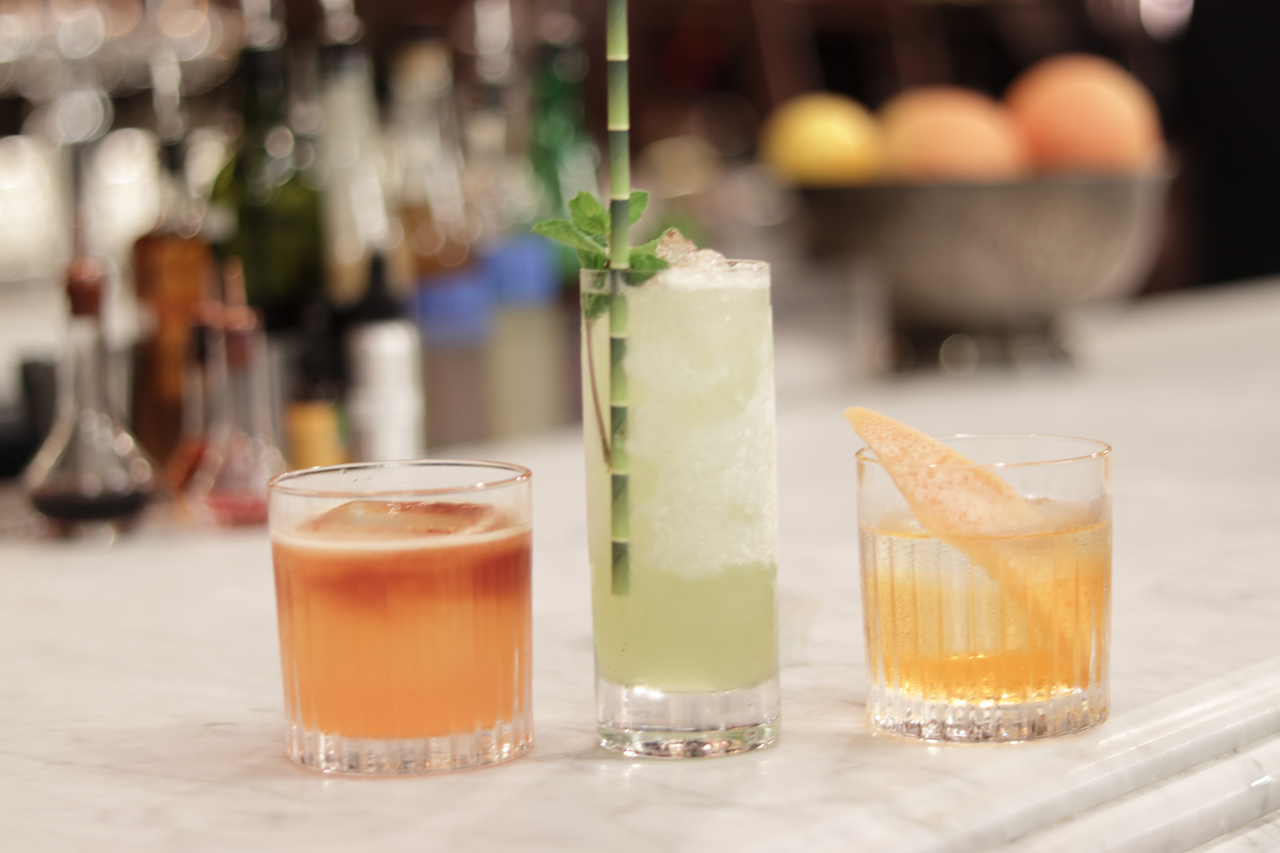 three cocktails on a marble bar counter